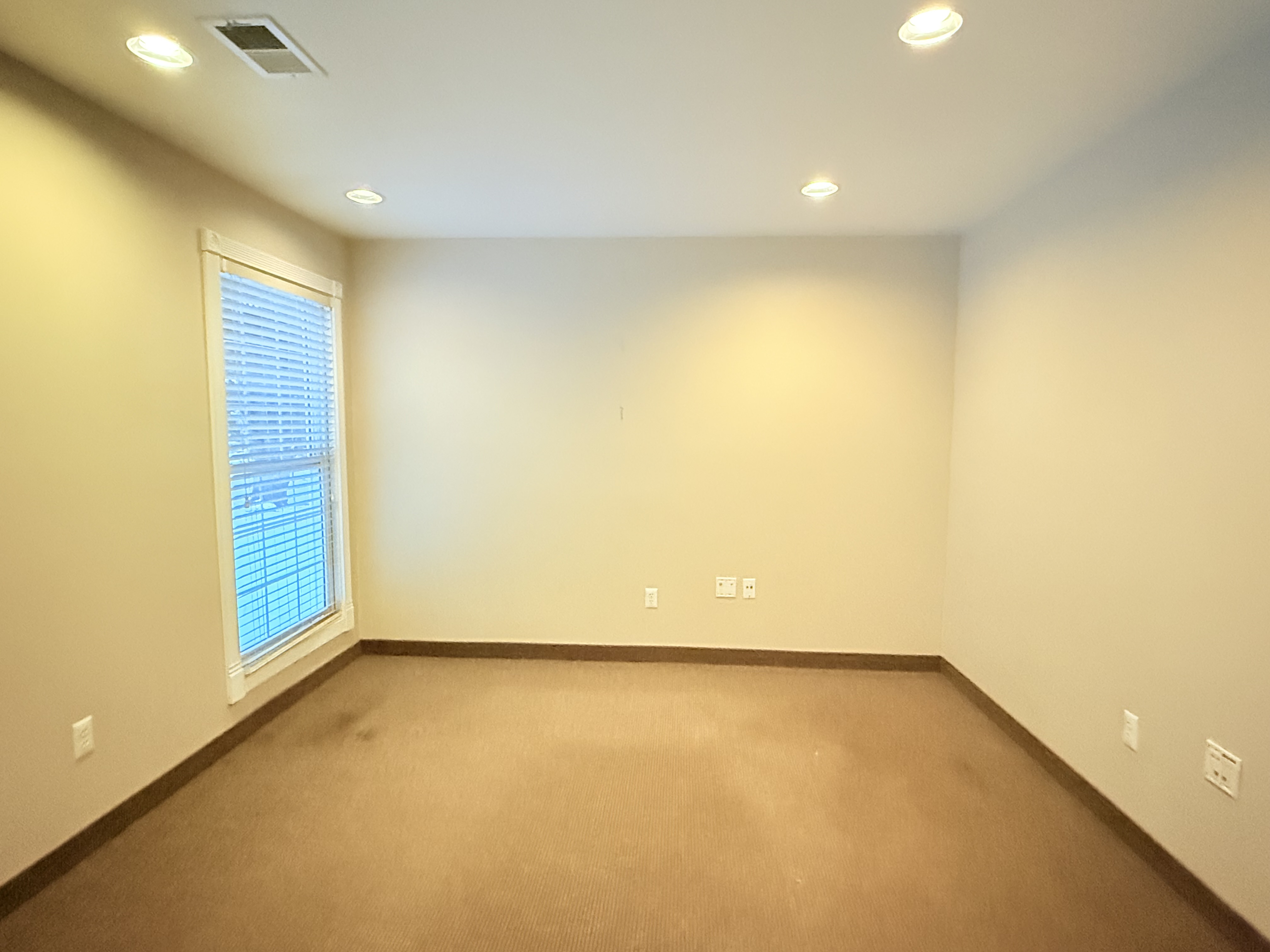 Suite 105 — clean carpeted private office with window and recessed lighting